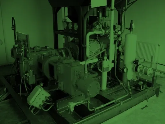 A green lit room with pipes and machinery.
