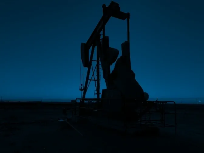 A silhouette of an oil well at night.